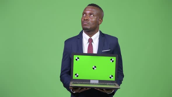 Young Happy African Businessman Thinking While Showing Laptop