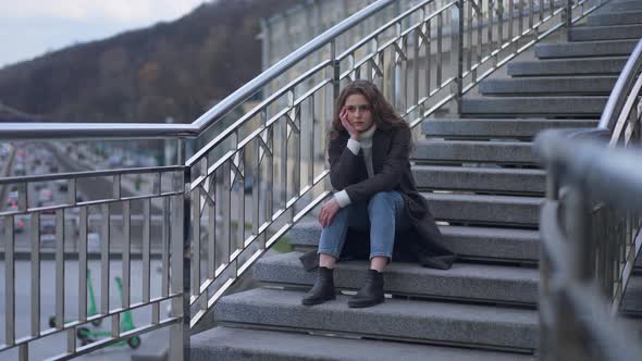Wide Shot Portrait of Hopeless Depressed Young Woman Sitting on City Stairs Sighing Thinking