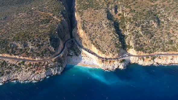 People Swim on Light Blue Sea in the White Sandy Beach Near the Rocky Mountainside