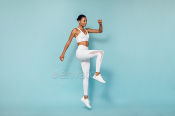 Fitness woman doing cardio training. Young female in sportswear jumping in studio.