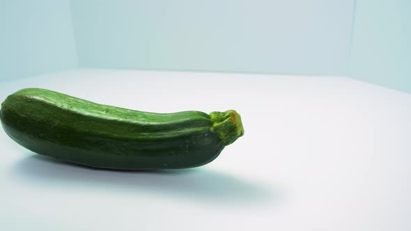 Green fresh zucchini squash rotates on a light blue background, healthy food, concept, medium close