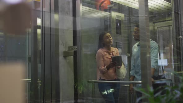 Video of diverse businesswoman and businessman talking in elevator