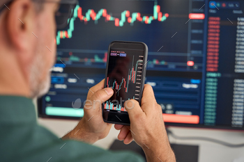 stock trade market on smartphone risk digital price data in mobile app buying bank shares, doing investment strategy analysis on phone. Over shoulder.