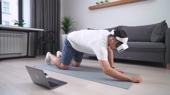 Young Man in Virtual Reality Glasses Performs a Plank Sports Using Modern Technology in