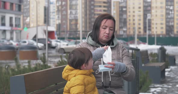 A Mother Puts Protective Mask on Herself and on Her Little Son