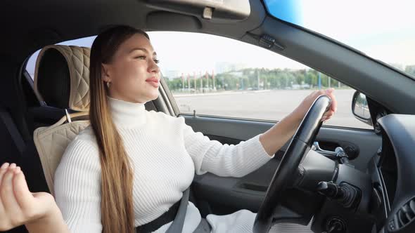 Fashionable Model in White Sings Holding Car Steering Wheel