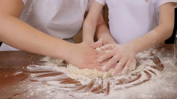 Closeup of Mother and Child Kneading Dough Together in the Kitchen