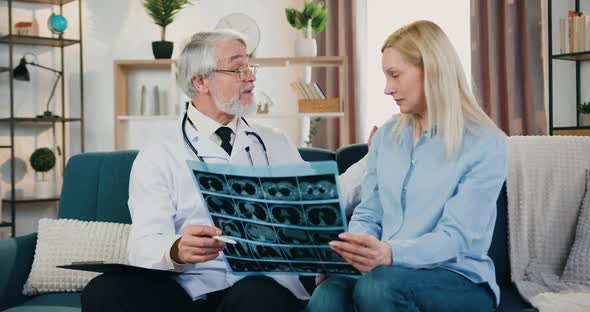 Family Doctor Calming His Female Patient while Explaining Results of X-ray Scan