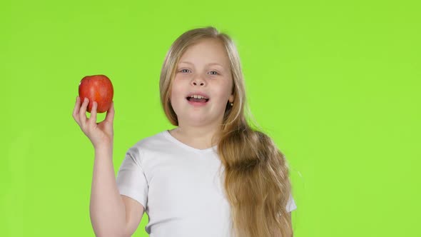 Little Girl Bites an Apple and Shows a Thumbs Up. Green Screen