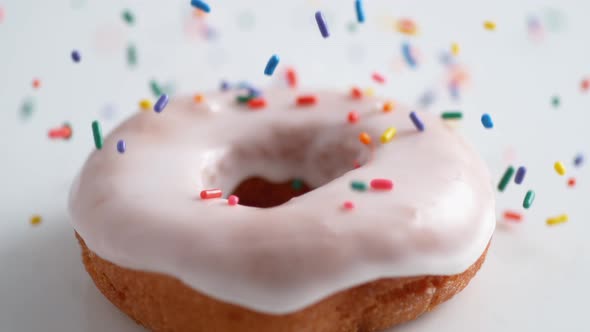Sprinkling candy chocolate on frosted doughnut. Slow Motion. alt