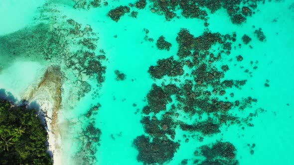 Wide angle fly over travel shot of a sandy white paradise beach and blue ocean background in colourf