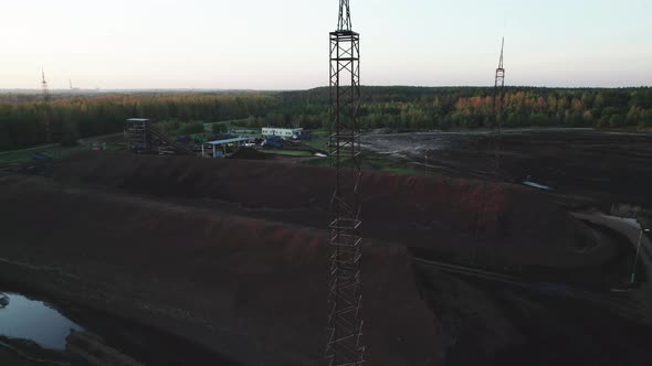 Metal Masts Near Piles of Lignin Stored in an Open Warehouse in a Wooded Area