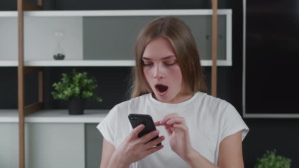 Shocked Young Woman Looking at Smartphone. Unpleasantly Surprised Female with Bad News