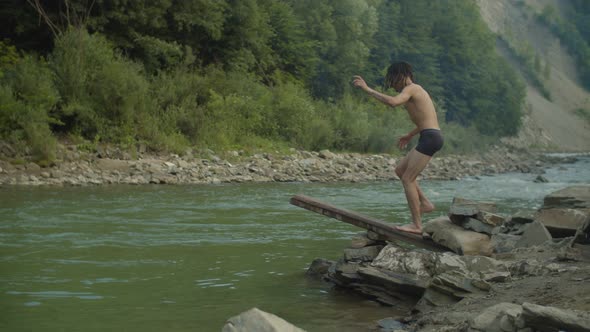 Cheerful Man Diving Into Mountain River Off Wooden Springboard