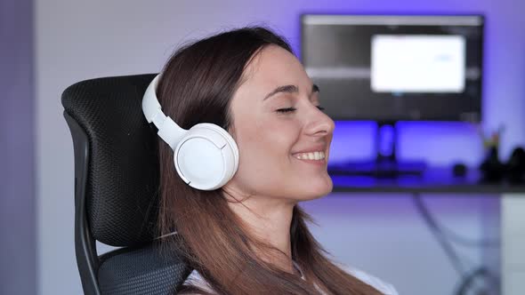 Appeased Young Woman Relaxing on Comfortable Armchair with Eyes Closed Wearing White Headphones