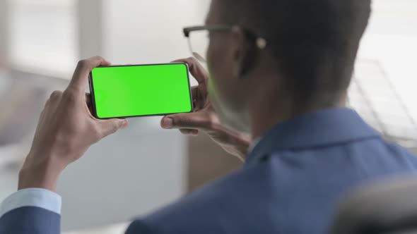 Young African Businessman Looking at Smartphone with Chroma Screen