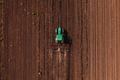 Green tractor vehicle with tiller attached performing field tillage before the sowing season - PhotoDune Item for Sale