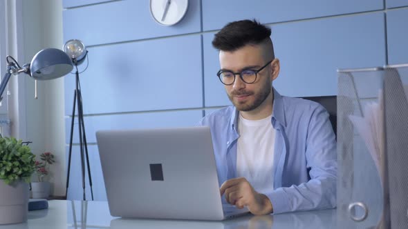 Handsome businessman working on an office. Focused young man typing on a laptop