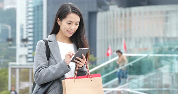 Woman use of smart phone and holding shopping bag