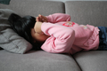 a upset child girl cover her face with hand lying on sofa  - PhotoDune Item for Sale
