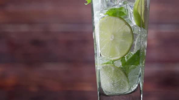 Close-up Refreshing Soda Tonic, Pour Carbonated Water Into a Glass of Lime and Ice, Cold Mojito