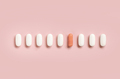 Mix of medical pills with one pink capsule in a line on light pink top view. Dietary supplements - PhotoDune Item for Sale