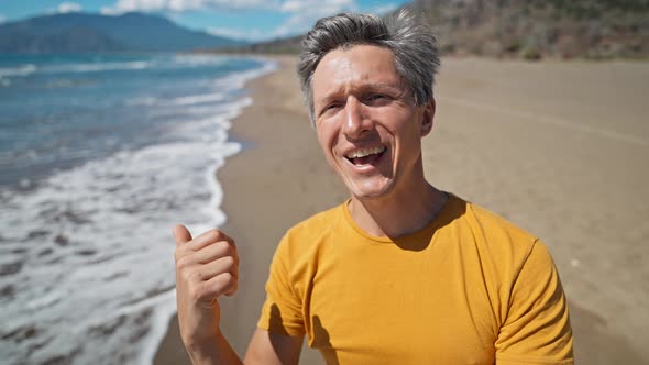 Happy Middle Aged Greyhead Man Takes Selfie at Sea Coast with Waves Enjoying Sunny Day on Beautiful