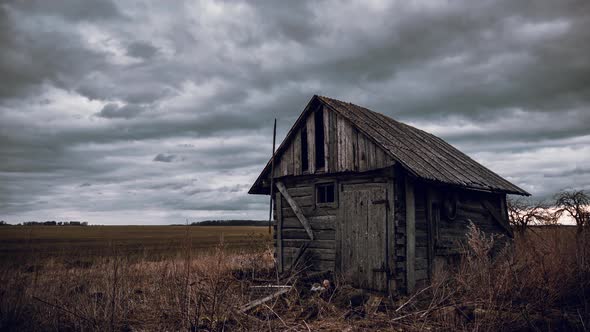 Old abandoned wooden barn in the fields and cloudy sky movement time lapse video.