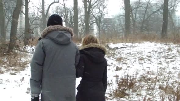 Couple walk by camera on winter forest path