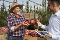 Senior farmer and sales representative talking over digital tablet on apple orchard - PhotoDune Item for Sale