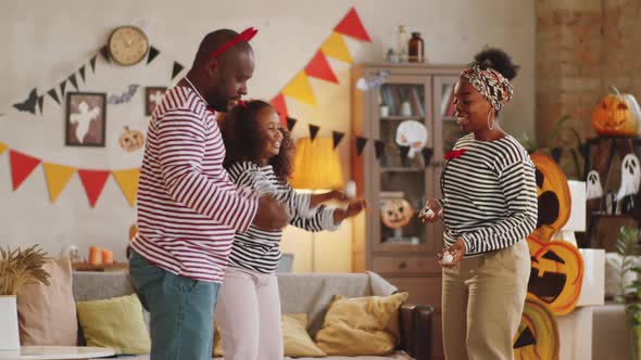 Cheerful Black Family Juggling with Eyeball Toys on Halloween at Home