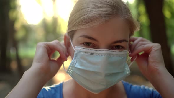 A Woman Wears a Medical Mask in a Park