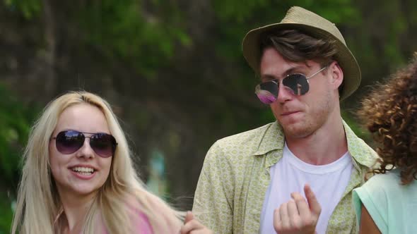 Cheerful Couple Wearing Sunglasses Dancing, Smiling at Summer Party With Friends