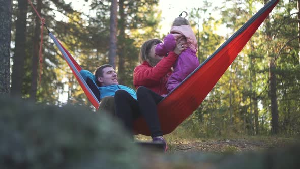 Family Vacation Camping Relax. Dad, Mom, Little Daughter on Hammock Together