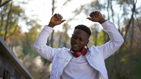 Front View Carefree Satisfied Man Raising Hands Smiling and Looking at Camera Standing in Sunrays