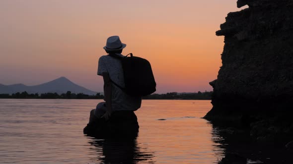 Tourist Taking a Rest on the Stone in the Sea