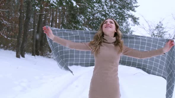 Happy Woman Wearing Scarf and Spinning on the Winter Forest Background