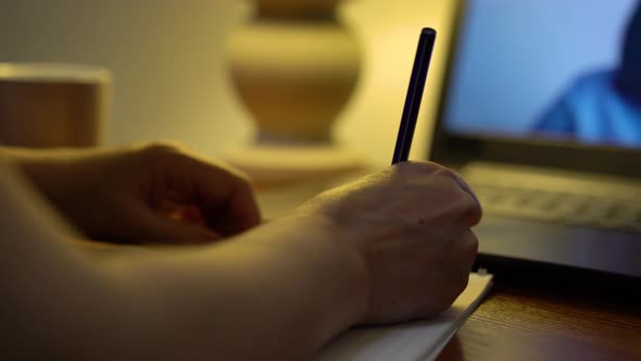 Female hands writing down lecture of professor teaching online