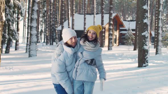 Young Cheerful Couple in a Winter Forest Man and Female Take a Photo on Camera Against the