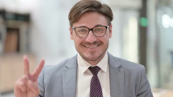 Portrait of Successful Businessman Showing Victory Sign with Hand