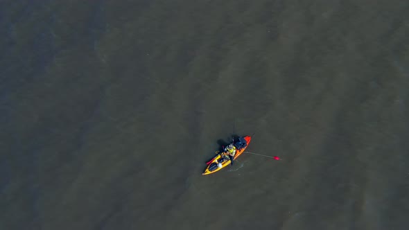 A man in a canoe fishing for food. Calm waters, Aerial, slow movement, top view. River over capital