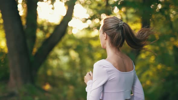 A Young Woman Runner is Training in Summer Park