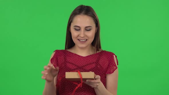 Portrait of Tender Girl in Red Dress Is Opening the Gift, Very Surprised and Rejoicing. Green Screen