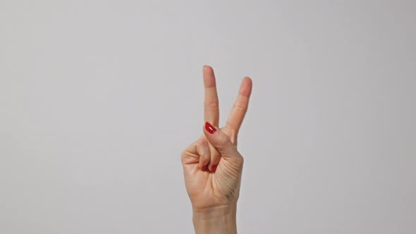 Woman raising two fingers up and showing peace or victory symbol or letter V