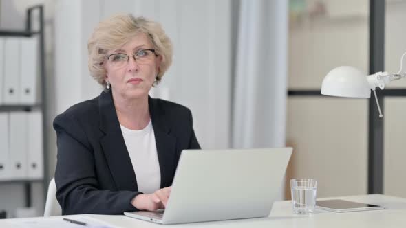 Old Businesswoman with Laptop Looking at Camera