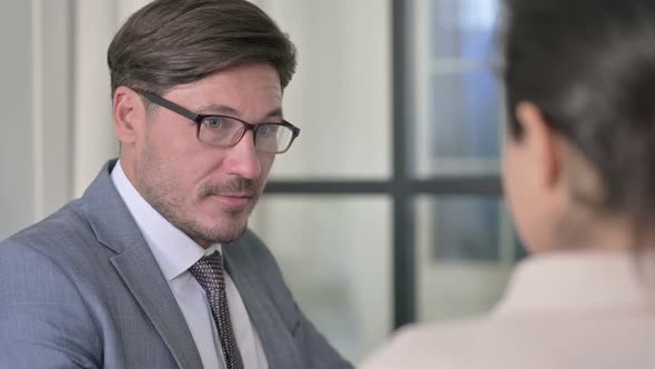 Close up of Serious Middle Aged businessman Talking to Female