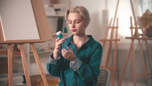 A Young Woman Artist Opening Up a Blue Paint Tube