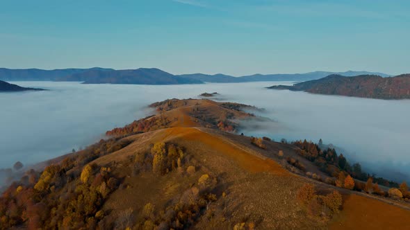 Aerial View of Sea of Fog Floating Rolling Over Mountain Valley Hills Islands at Sunrise Golden Hour