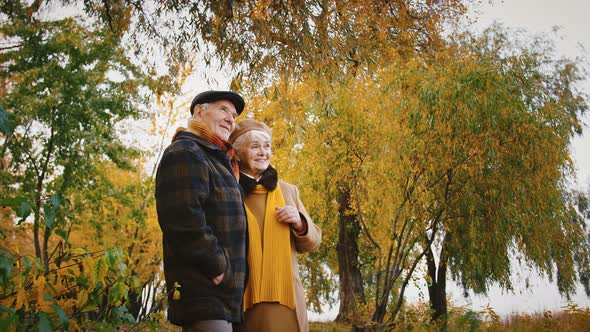 Happy Retired Pair Smiling Discussing Something They Seeing at Distance Standing at City Park with