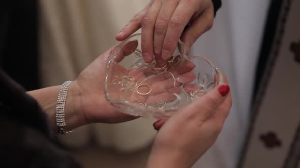 Wedding Rings in Plate with Holy Water During Matrimony. Priest Takes One Ring